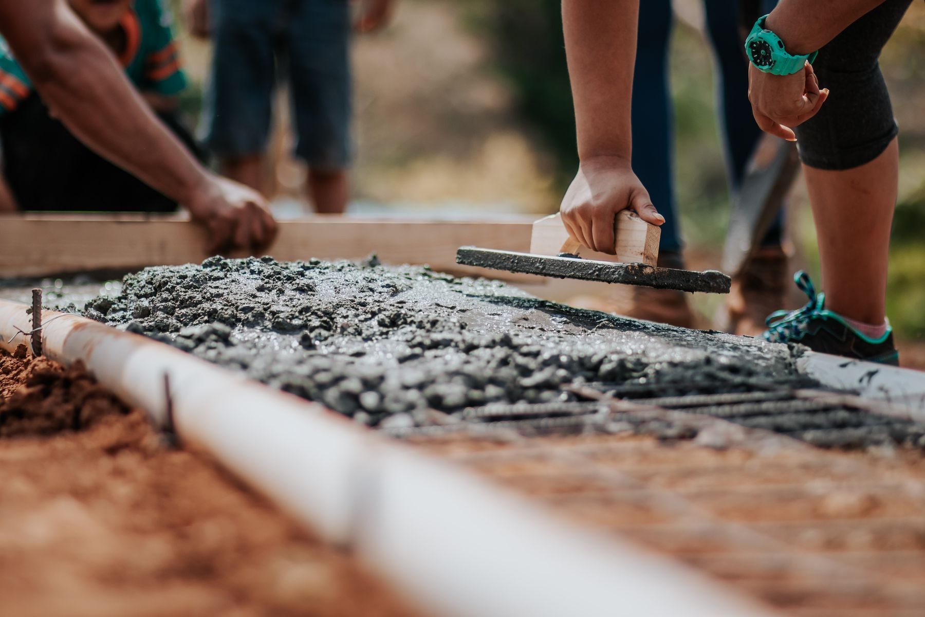Crew finishing a freshly placed concrete slab with a hand trowel